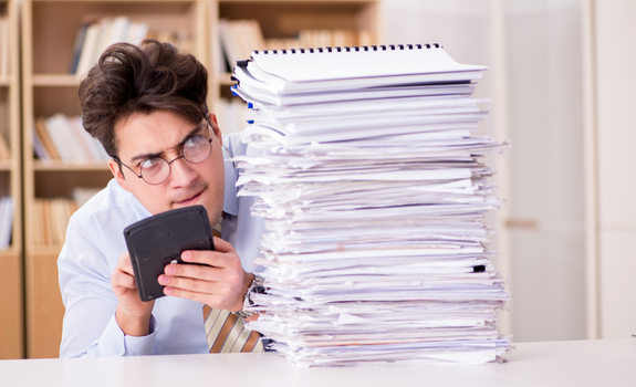 Small business owner overwhelmed by stacks of paperwork before receiving professional bookkeeping cleanup services